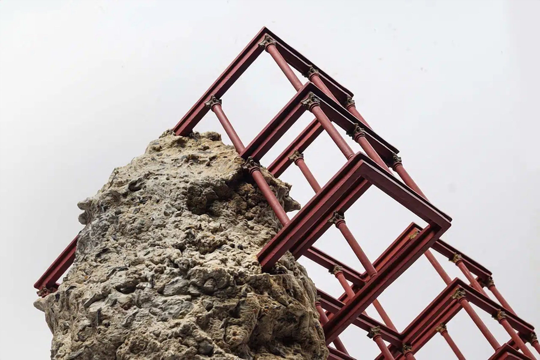 CELINE Art Project: a red framework sculpture resting on a stone mass