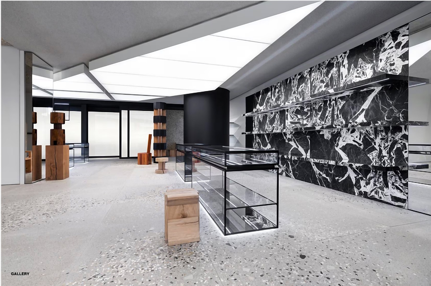 Retail mood board: boutique with a black and white veined stone wall, glass display case and carved timber volumes